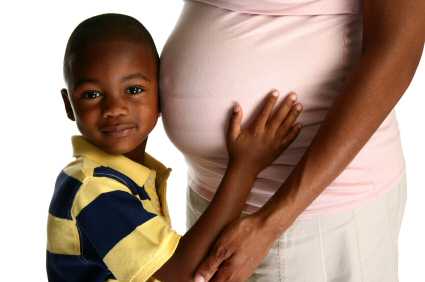 A pregnant woman with her young son hugging mummy's tummy